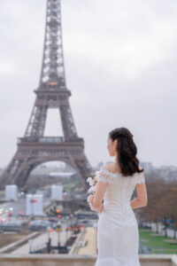 淡いピンクのブーケを持つ花嫁の後ろ姿とエッフェル塔