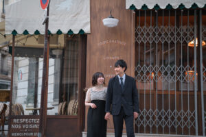 パリのカフェを背景に微笑むふたりの姿