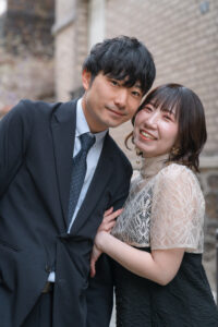 パリの石畳を背景に腕を組み微笑むふたり