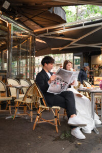 テラスの丸テーブルで新聞を読むカップル