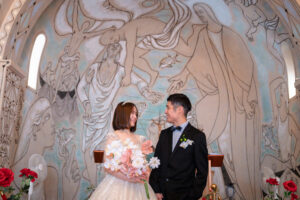 ジャン・コクトーの絵を前に微笑みあう新郎新婦