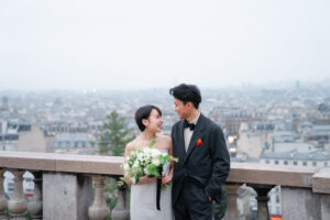 パリ モンマルトルの丘から見えるパリの街並みの前で微笑みあうカップル