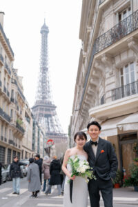 エッフェル塔の前でこちらを見るカップル
