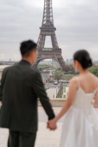 エッフェル塔を手をつなぎながら見つめるカップル