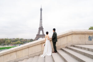 エッフェル塔の前で手をつなぎあうカップル
