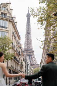 街並みの間から見えるエッフェル塔と手をつなぐカップル