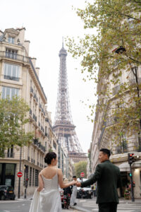 街並みの間から見えるエッフェル塔と手をつなぐカップル
