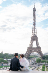 エッフェル塔の前で座って微笑みあうカップル