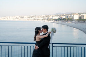 ニースの海をバックにハグをする幸せなカップルの前撮り写真