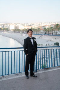 ニースの海を背景にポーズを決める新郎の全身ソロポートレート