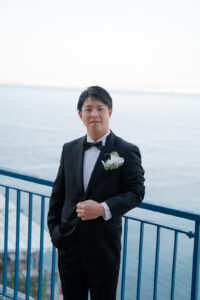 ニースの海を背景にポーズを決める新郎の半身ソロポートレート