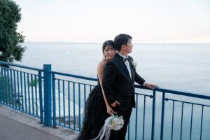 ニースの海を背景に新郎を後ろからハグする新婦