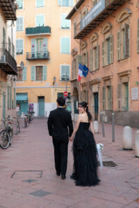 ニース旧市街のカラフルでパステルな街並みを歩く新郎と後ろを振り向く新婦