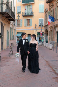 ニース旧市街のカラフルでパステルな街並みを手を繋ぎながら歩く新郎新婦