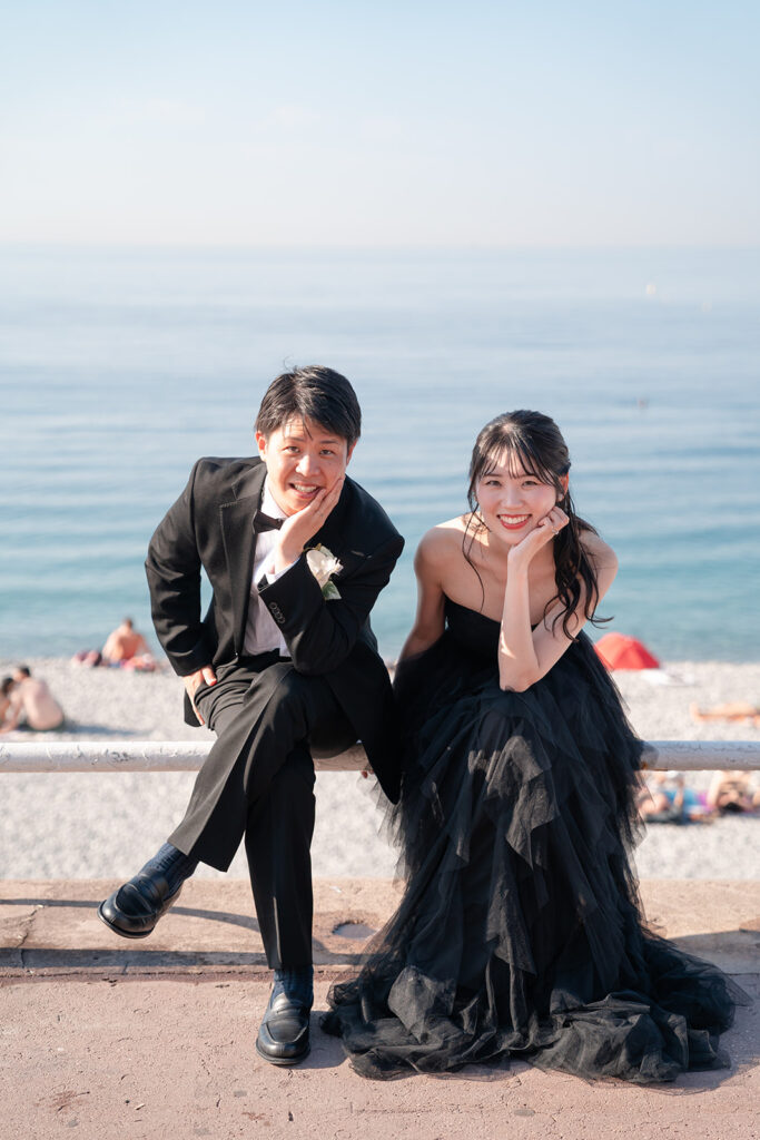 ニースの海を背景に顎に手を置いてポーズする新郎新婦