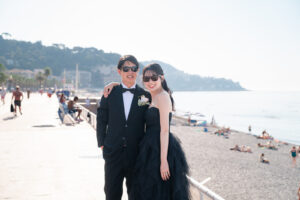 ニースの海岸でサングラスをかけて微笑む新郎新婦