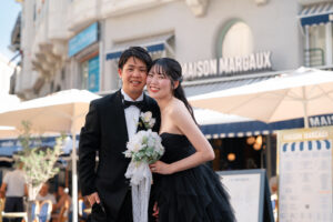 Netflixシリーズ『オフライン・ラブ』の舞台となったニースのカフェ「Maison Margaux」の前で笑顔で寄り添う新郎新婦